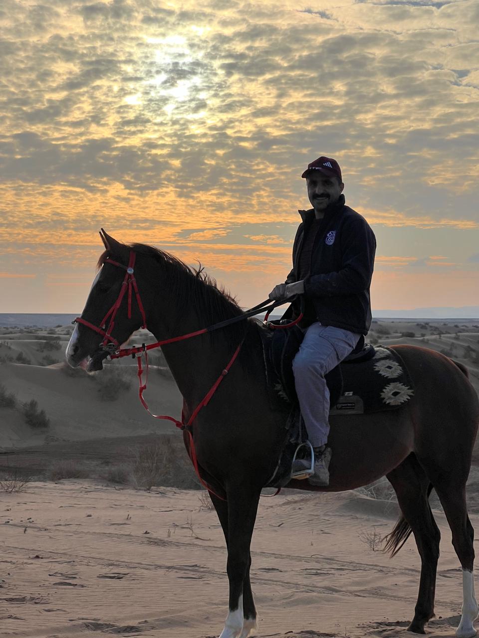 Mohammad Fdoul riding his horse near the desert camp at Desert Wolf Horse Riding